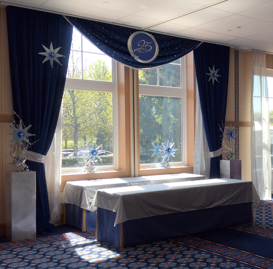 scénographie événementielle d'un point d'accueil client avec des décorations de rideaux bleu à paillettes et des étoiles argentés